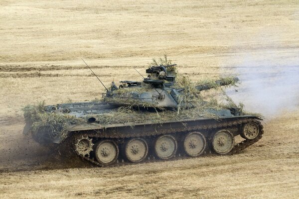 A military tank disguised with straw in a field