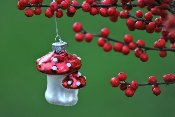 Auf den Zweigen von Beeren und Weihnachtsspielzeug auf grünem Hintergrund