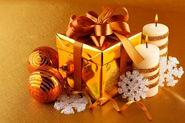 A Christmas gift in a golden box with a ribbon. New Year candles on a yellow background