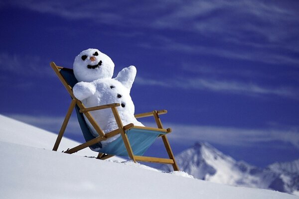 Nouvel an, bonhomme de neige dans le fauteuil a fond de montagnes et de neige