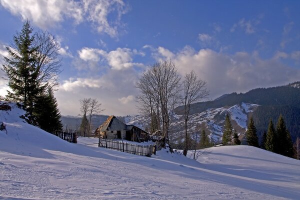 Winterlandschaft mit schneebedeckten Bergen und einsamem Haus