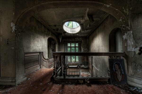 Rundes Fenster über einer alten Treppe in einem verlassenen Herrenhaus