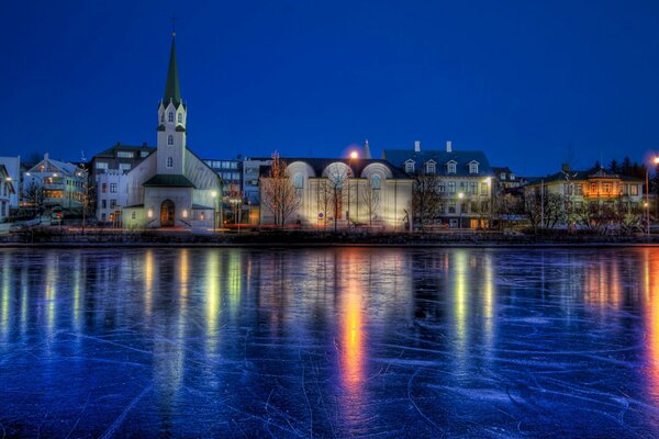 Vistas nocturnas de Reykjavik sobre un estanque de hielo de invierno encadenado