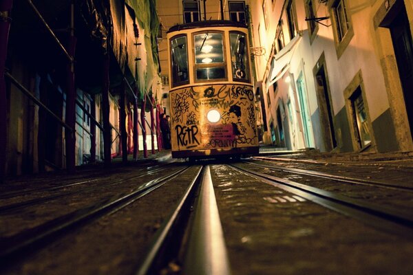 Tranvía nocturno sobre rieles en una calle estrecha