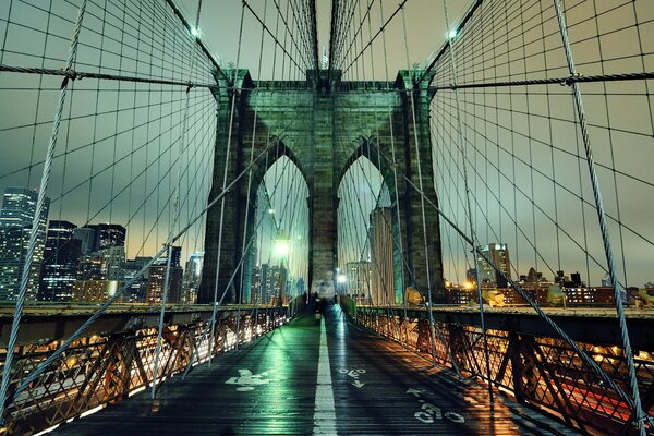 El puente de Brooklyn de nueva York, filmado por la noche en medio de las luces ardiendo de los rascacielos