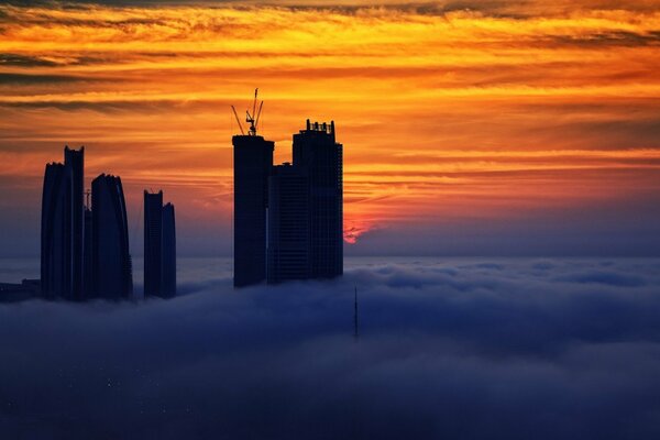 Gratte-ciel dans les nuages au coucher du soleil