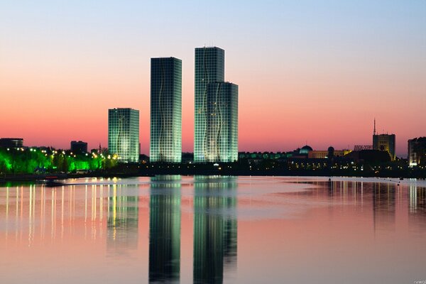 Los rascacielos de Astana se reflejan en el agua al atardecer