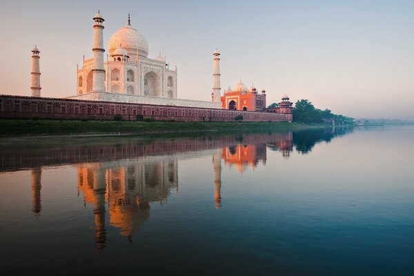 The Taj Mahal is reflected in the smooth surface of the calm river