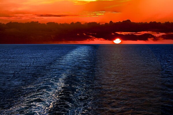 Coucher de soleil rouge sur la mer. Nuages au-dessus de l eau