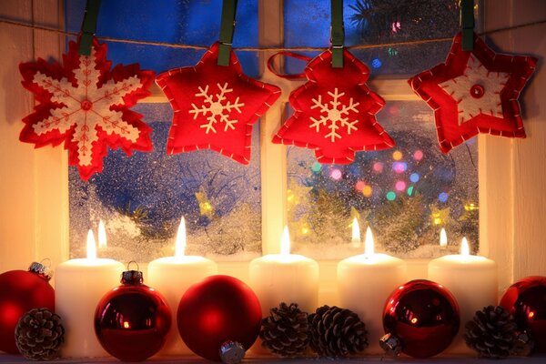 Weihnachtsschmuck. Kerzen und Spielzeug auf einem schneebedeckten Fenster