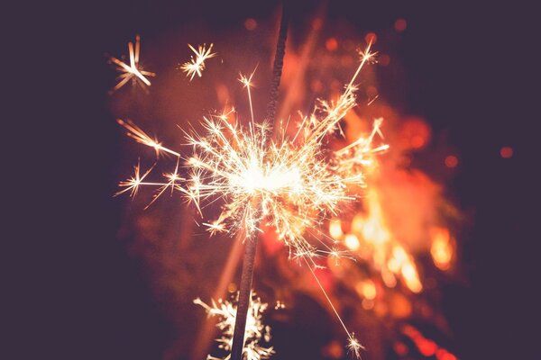 A burning sparkler on a dark background