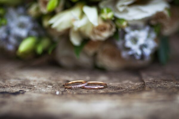 Two gold rings close-up on the background of a delicate bouquet