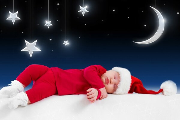 Un petit enfant en costume de père Noël dort sous un ciel étoilé