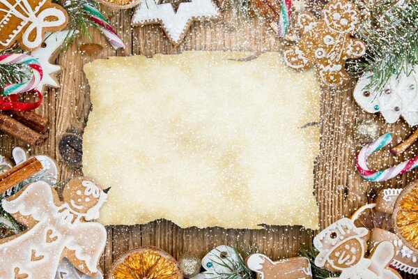 Juguetes de Navidad en una mesa de madera alrededor de una hoja en blanco para felicitaciones