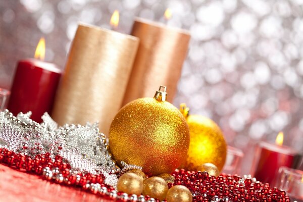 Bougies allumées et boules de Noël dorées se trouvant sur une table parsemée de perles