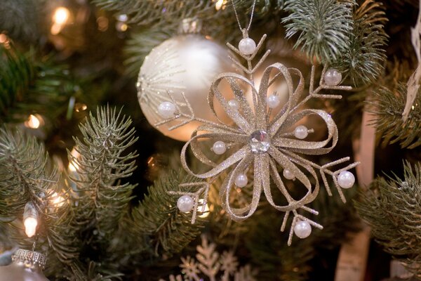 Fleur avec des perles et un ballon sur un arbre de Noël éclairé par des lumières