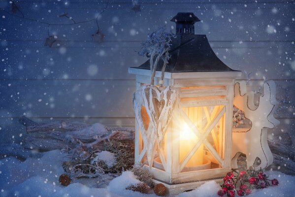 A candle holder with a deer and ornaments in the snow