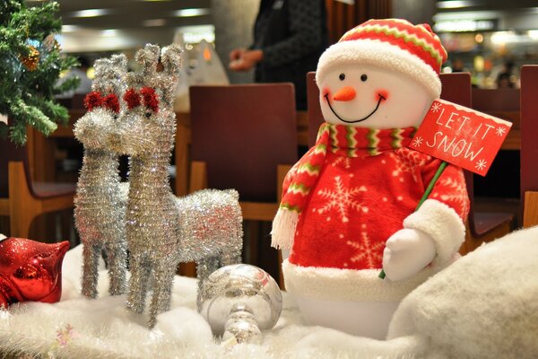 Schneemann mit Hirschen in der Nähe des Weihnachtsbaumes