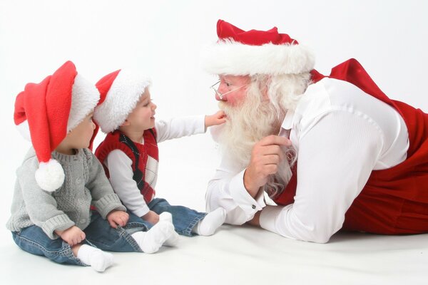 Santa Claus habla con dos niños con sombreros rojos