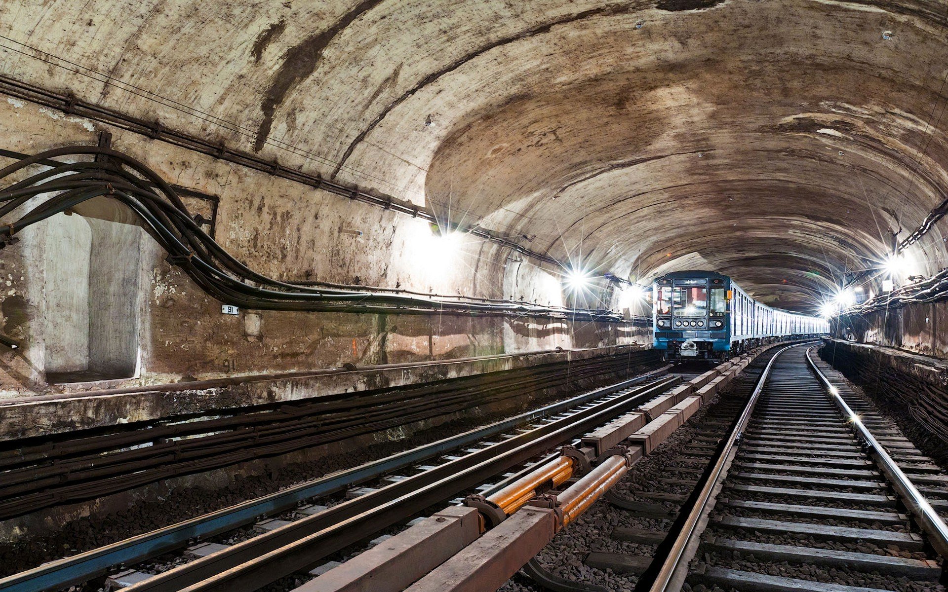 underground subway rails sleepers tunnel train wire cables arch light bulbs light