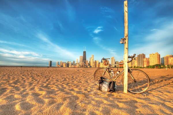 The beach, there is a pole on it, against which a bicycle is leaning