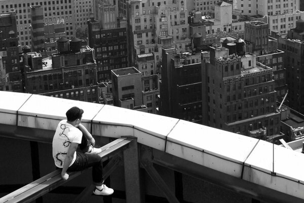 View of the city from a height. Photo of the guy from the back. The guy on the roof