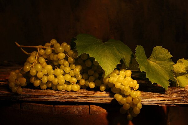 Racimos de uvas blancas con hojas en una mesa de madera