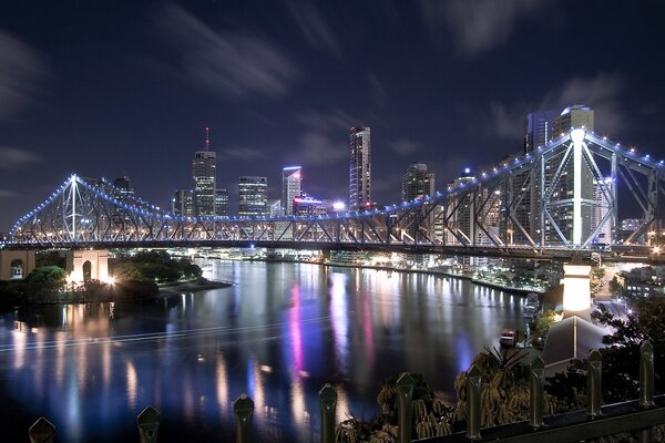 Luci incandescenti sul ponte. Case e grattacieli sul fiume Night City