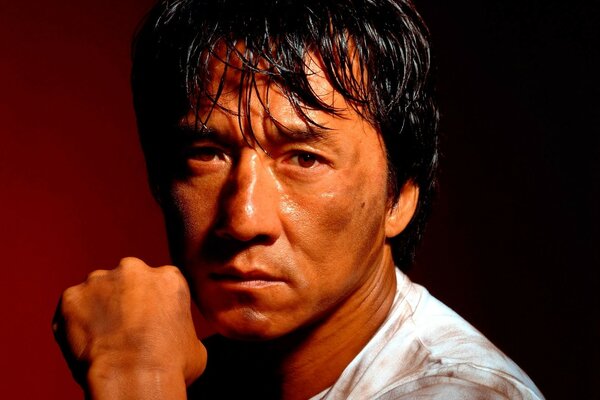 Jackie Chan sits with a fist in his hand