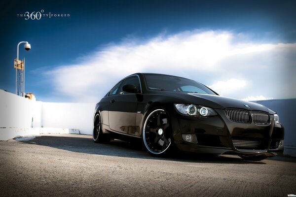 Black BMW on the contrast of white clouds