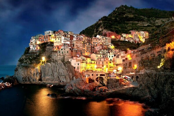 Una ciudad italiana nocturna en las rocas junto al mar