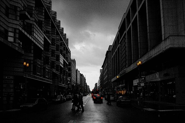 Berlin, a night street with high-rise buildings, cars, people, against a cloudy sky