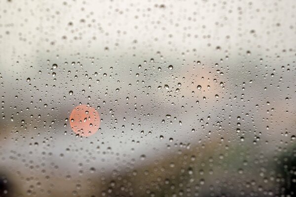 The window is covered with raindrops