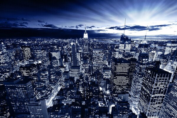 Night city, dark streets with multi-storey buildings on the background of sunset