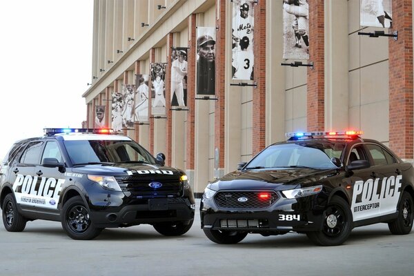 Dwa samochody ford police interceptor obok stadionu