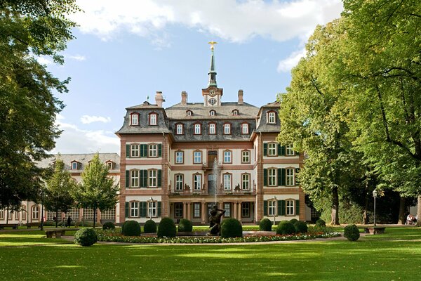 Grüne Landschaft des Parks im Sommer . Blauer Himmel und schicke Architektur des Hauses