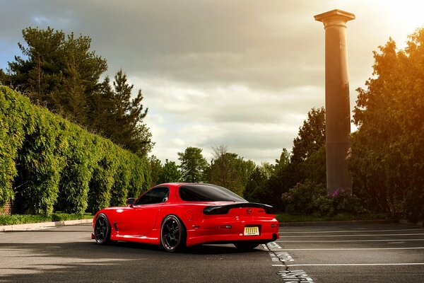 Roter Mazda rx-7 auf einem Parkplatz unter Bäumen