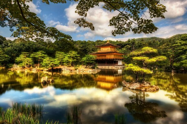 The gold of the Japanese temple pagodas is reflected in the waters and clouds