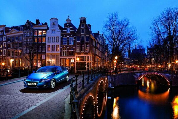 A Honda car rides on a lighted bridge