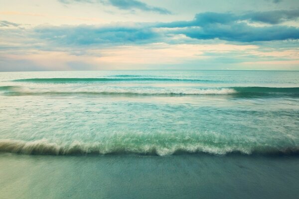 A powerful wave surged onto the shore of a sandy beach