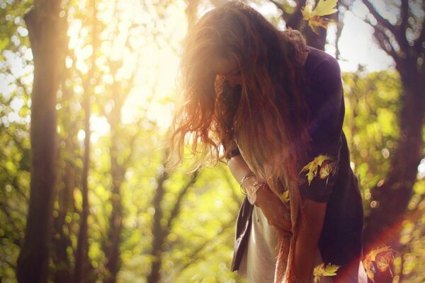 Chica de pelo largo en la luz del sol en el fondo de los árboles