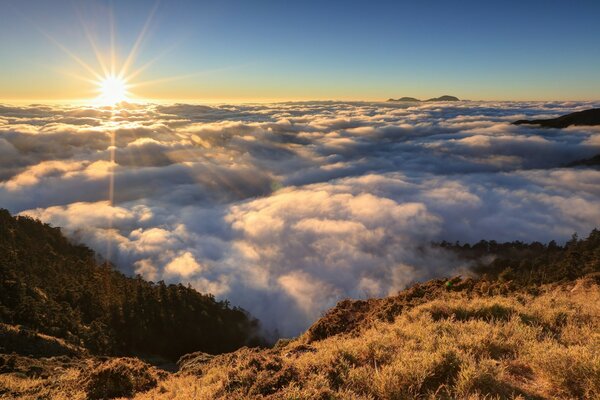 Die Sonne scheint über Wolken und Bergen