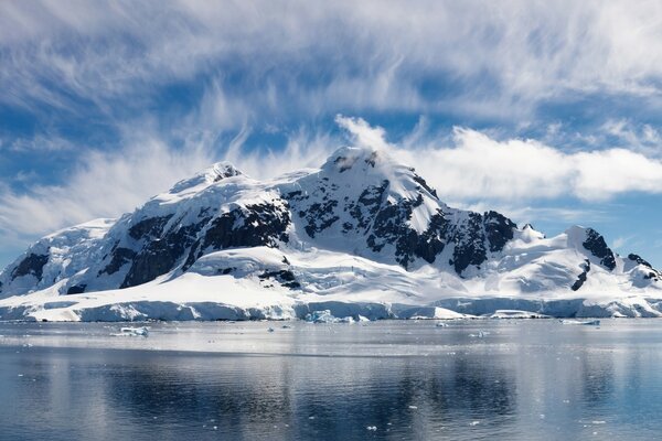 Montagne innevate tra le nuvole e un lago nel ghiaccio