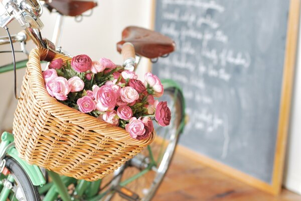 Fleurs dans un panier de vélo sur fond de planche