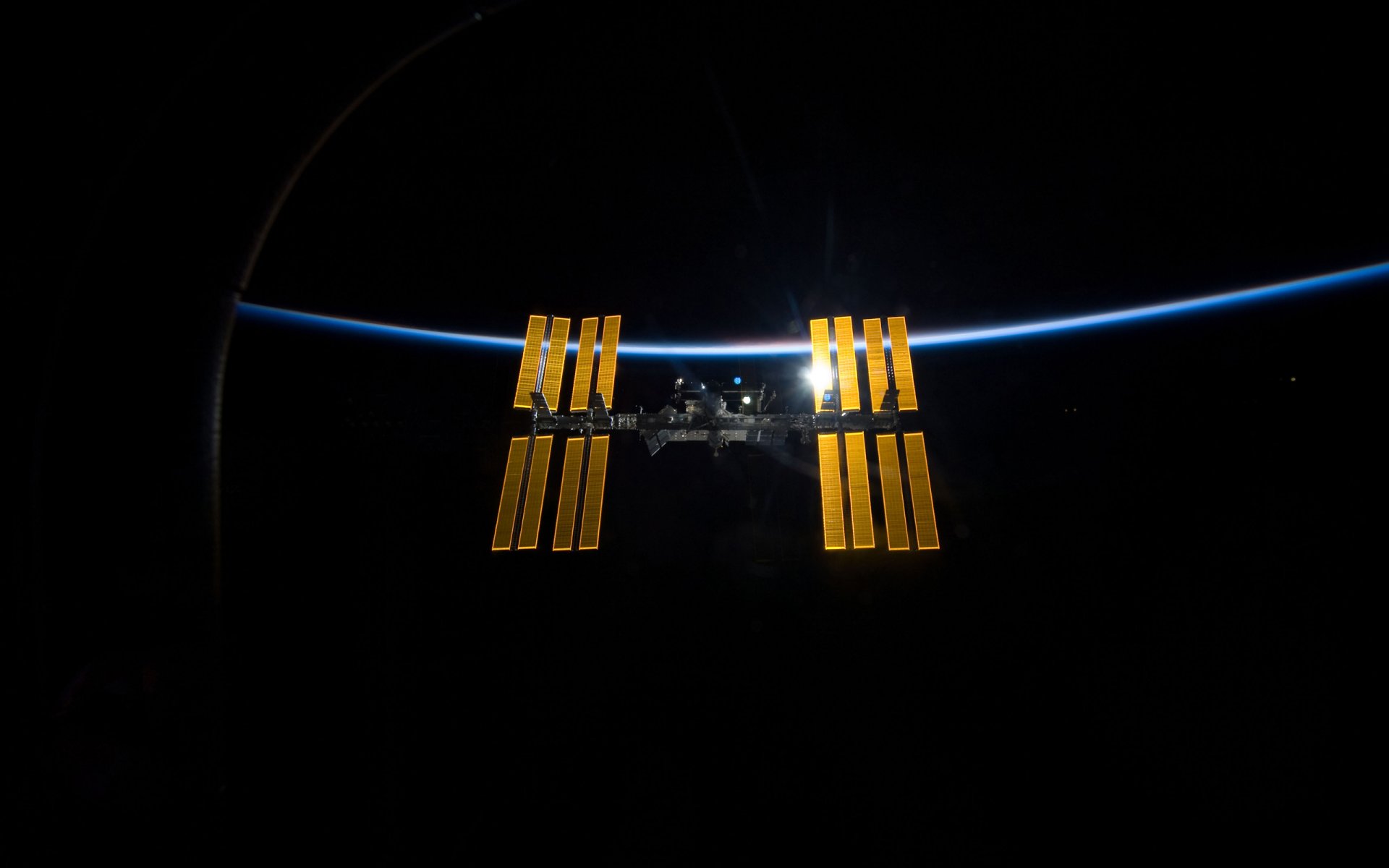 international space station illuminated space iss illuminated orbit earth satellite dish ship ready to dock solar cells panels modules planet surface horizon brightness light background