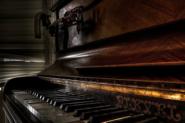 Primo piano di un vecchio pianoforte in legno in una stanza buia