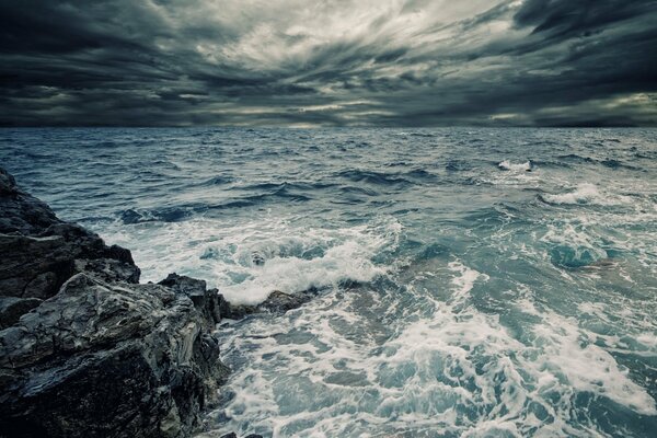 Waves crashing against rocks under a cloudy sky