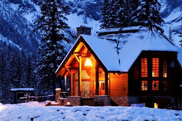 Casa cubierta de nieve cerca de los árboles en las montañas