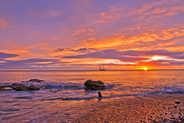 A sailboat in the distance at sunset. Calm and serenity of the sea