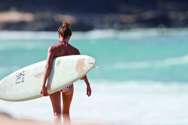 A girl with a surfboard on the background of the ocean